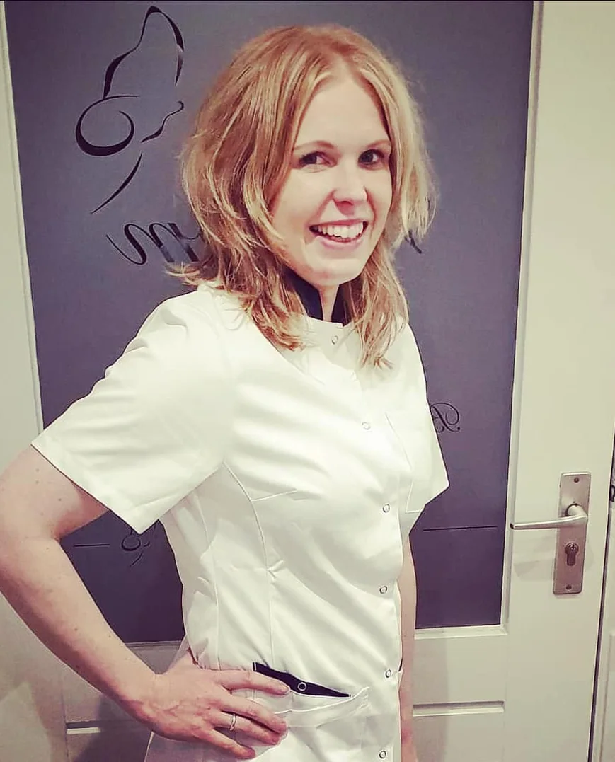 Evelien Vaags lacht in haar praktijk, in een witte behandeljas